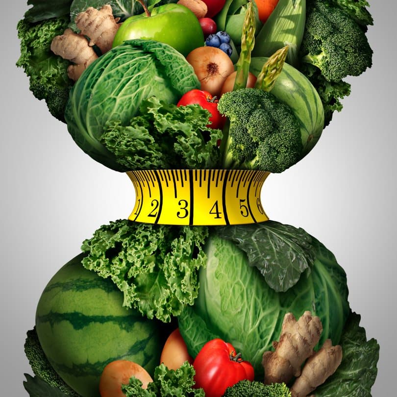 Vegetables arranged in the shape of a body with a tape measure around the waist.