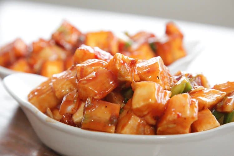 A bowl of chilli paneer in a glossy sauce.